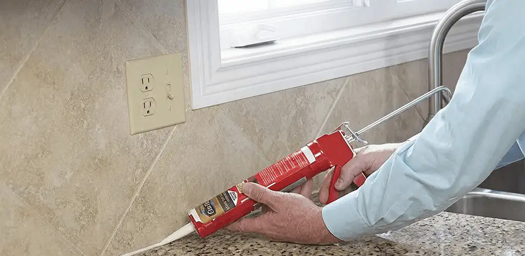 Handyman applying caulk along a kitchen backsplash and countertop seam in Raleigh, NC