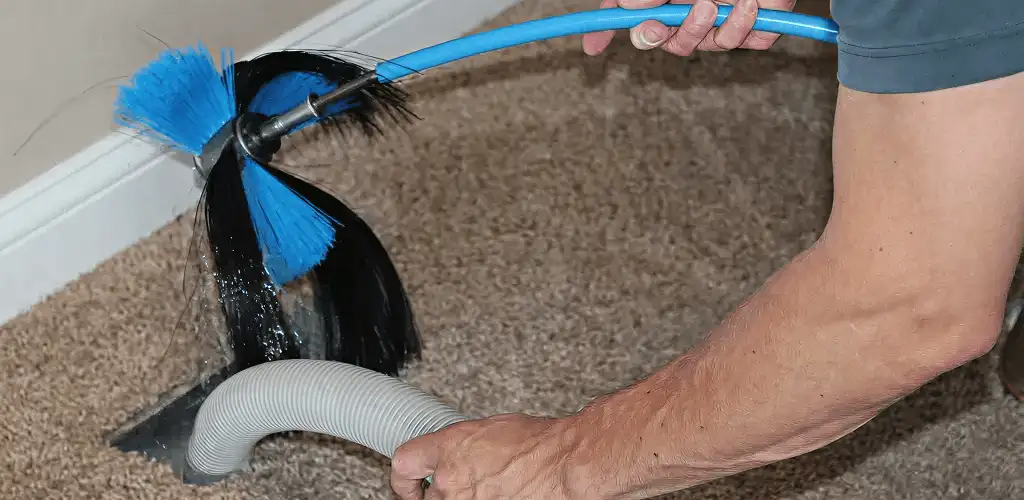 Dryer vent cleaning technician brushing lint from a vent line in Raleigh, NC