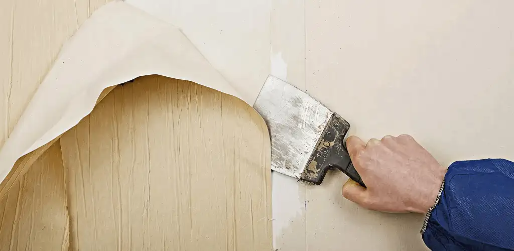 Handyman removing wallpaper with a scraper for wall preparation in Raleigh, NC