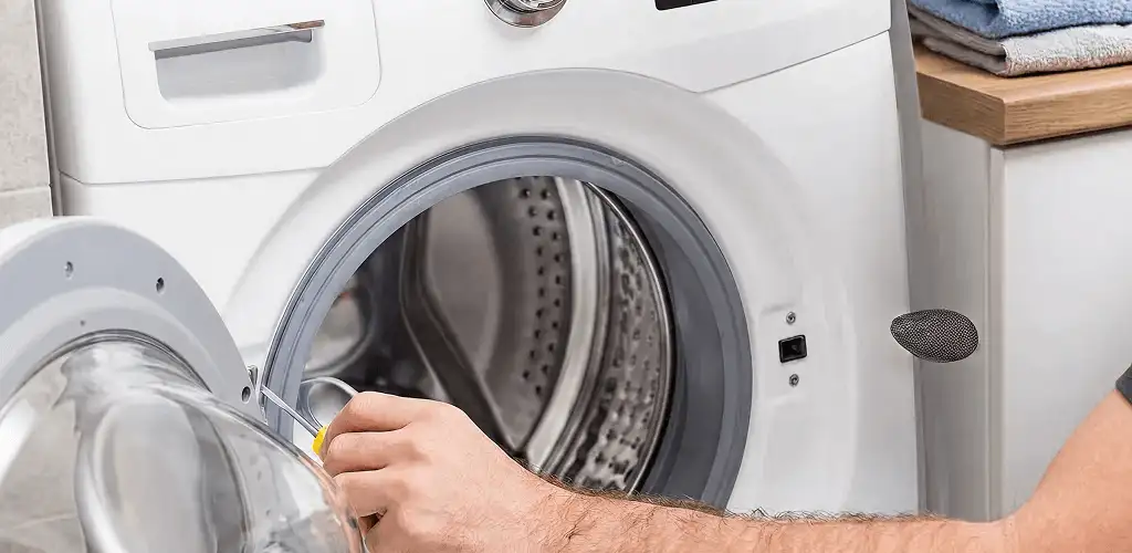 Handyman repairing a front-load washing machine and inspecting the drum in Raleigh, NC