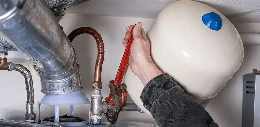 Water heater repair technician tightening plumbing connections near a tank unit in Raleigh, NC