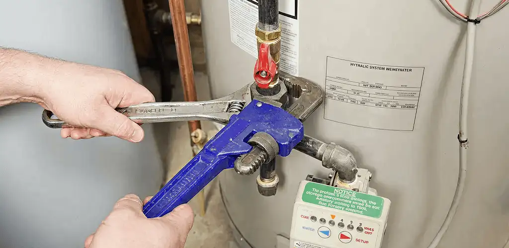 Water heater repair technician tightening the shutoff valve and supply line in Raleigh, NC